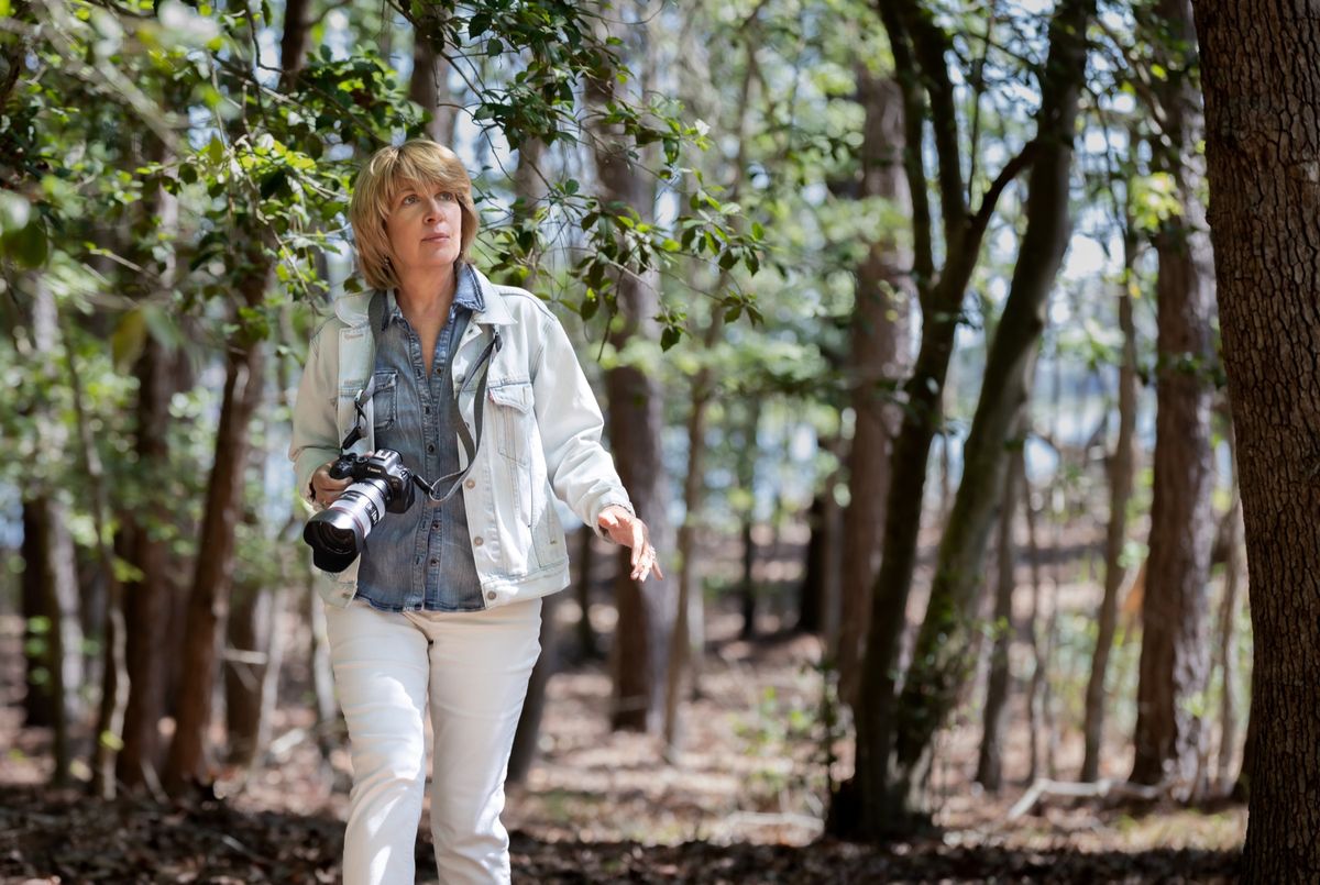 Photographer Sharon Thorpe walks through the woods with her camera.